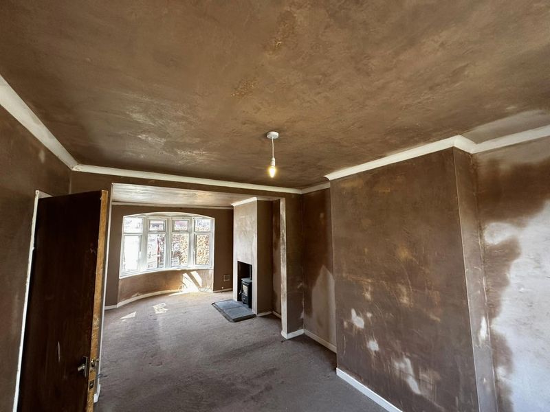 A through lounge with the walls and ceiling skimmed, the plaster drying pale in patches