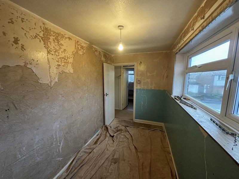 A box room with patchy old plaster hacked back on the walls